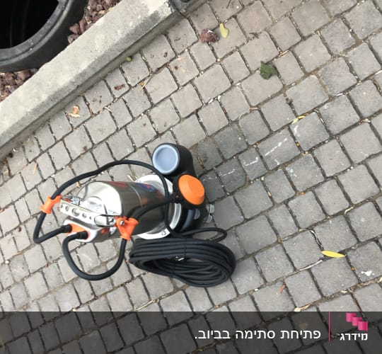 משאבה עם כבל שחור על מדרכה מרוצפת